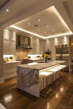 a large kitchen with marble counter tops and white cabinets