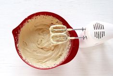 a red bowl filled with batter and a whisk