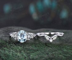 an oval cut aqua blue topazte and diamond engagement ring set on a mossy surface