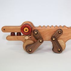 a wooden toy alligator with red eyes and teeth