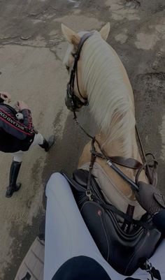 a person riding on the back of a white horse next to a black and brown bag