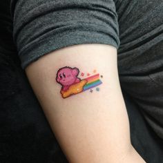 a person with a small tattoo on their arm that has a pink bear sitting on top of a rainbow