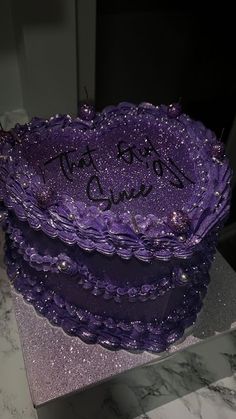 a purple cake with writing on it sitting on top of a counter