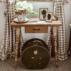 a wooden table topped with a potted plant next to a window covered in curtains