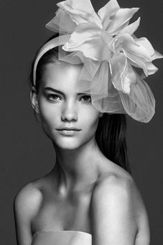 a woman with a flower on her head wearing a white dress and posing for the camera