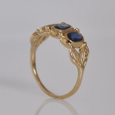 "A beautiful handmade gold 3 Sapphire gold ring for a woman. This solid gold and Sapphire ring is all hand made engraved by me in lost wax technique. The ring is 14k solid gold all made as one single piece including the three stone bezels, in which three beautiful blue Sapphire stones are set and the two leaves on each side of the ring. The ring has a vintage style look that resembles a royal Sapphire ring. This blue Sapphire and gold ring will surly get attention to your finger. I am certain yo Handmade 14k Gold Sapphire Ring, Handmade Yellow Gold Sapphire Ring, Handmade 14k Gold Sapphire Promise Ring, Handmade Oval Sapphire Ring In 14k Gold, Elegant Handmade 14k Gold Sapphire Ring, Handmade Elegant Sapphire Ring In 14k Gold, Elegant Handmade Yellow Gold Sapphire Ring, Sapphire Gold Ring, Gold Ring Vintage