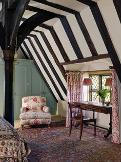 an attic bedroom with striped walls and wood beams on the ceiling is furnished with antique furniture