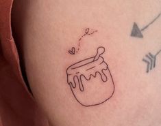 a small tattoo on the back of a woman's arm with a honey jar