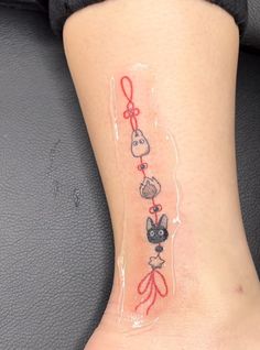 a small tattoo on the leg of a woman's foot with cats and bows