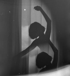 a woman standing in front of a window with her arms up and hands behind her back