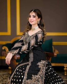 a woman in a black and gold dress sitting on a chair