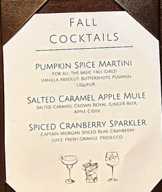 the menu for fall cocktails is displayed on a wooden plaque with white paper and black lettering