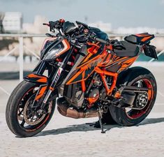 an orange and black motorcycle parked on the beach