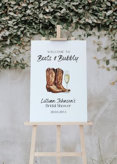 a welcome sign with cowboy boots and a glass of wine on an easel in front of a wall