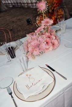 a table set with place settings, silverware and pink flowers in vases on it