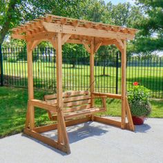 a wooden swing set in the middle of a park with a potted plant next to it