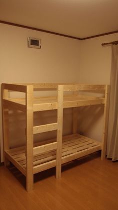 a bunk bed sitting on top of a hard wood floor next to a curtained window