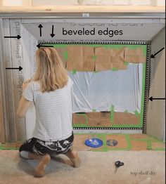 a woman sitting on the floor in front of a room with cardboard taped to it