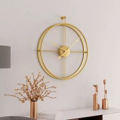 a clock that is on the wall next to a vase with some flowers in it