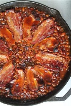 a skillet filled with bacon and beans on top of a stove