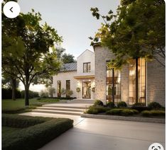 a large house with steps leading to it and trees in the front yard at dusk