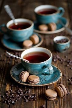 two cups of tea and some cookies on a table with coffee beans scattered around them