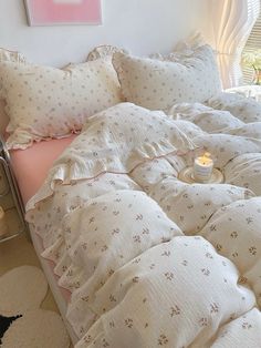 a bed with white comforter and pillows on it in front of a pink painting