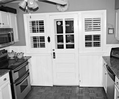 black and white photo of kitchen with stove, oven, microwave and cabinets in it