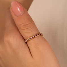 a woman's hand with a gold ring and pink nail polish on her nails