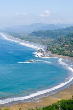 an aerial view of the ocean and beach with waves coming in from the shore line