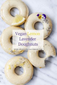 four vegan lemon lavender doughnuts on a marble surface with the words vegan lemon lavender doughnuts