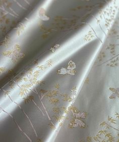 an image of a white and gold fabric with flowers on the side, close up