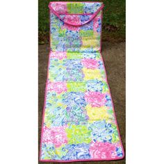 a pink and blue flowered sleeping bag on the ground with grass in the background