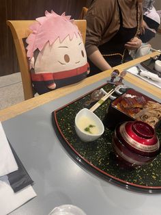 a person sitting at a table with some food on it and chopsticks in front of them