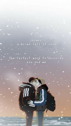 two people standing next to each other in front of the ocean with snow falling on them