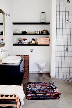 a bathroom with a sink, toilet and shelves in the wall next to each other