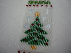 a beaded christmas tree ornament hanging on a wall