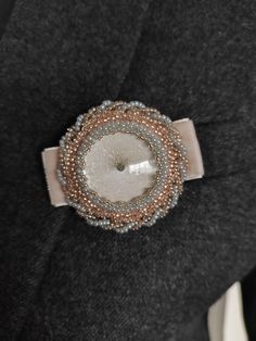 This exclusive handmade brooch is made of a round glass cabochon with a diameter of 3 cm, Japanese Toho beads and Czech Preciosa beads, genuine leather, nylon monofilament, steel clasp. Description             Length: 6cm/2.36in             Width: 5cm/1.97in  The color of the brooch is delicate, gray-beige. The back is trimmed with natural velor leather in light brown color. This piece is truly one-of-a-kind, made in a single edition. This intricately embroidered brooch will be the highlight of Unique Cabochon Brooches For Weddings, Unique Wedding Cabochon Brooches, Handmade Round Beads Brooches For Gifts, Silver Beaded Brooches As Gifts, Elegant Silver Beaded Brooches, Artisan Beads, Gems And Cabochons For Gifts, Elegant Beaded Brooches For Gifts, Artisan Round Beads Gems And Cabochons For Gifts, Handmade Round Brooch For Formal Events