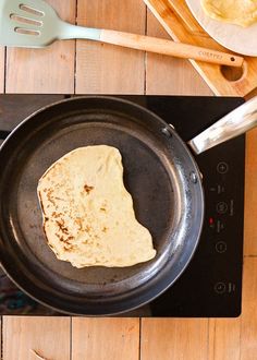 some food is cooking in a pan on top of a stovetop with utensils