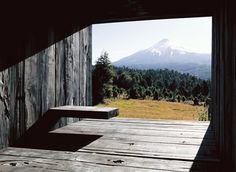 a wooden bench sitting in the middle of a room with a mountain view behind it