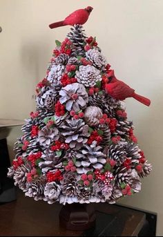 a christmas tree made out of pine cones and red birds sitting on top of it