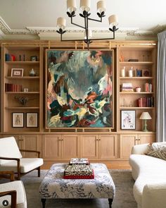 a living room filled with furniture and a large painting on the wall above it's bookshelves