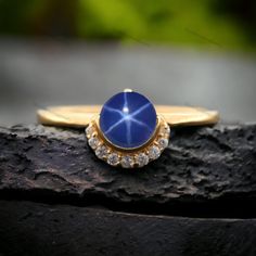 a gold ring with a blue stone surrounded by white diamonds on top of a piece of wood