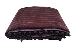 a maroon blanket with black pom poms on the bottom and purple trim around it