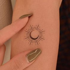 a woman's arm with a sun and moon tattoo on the left side of her body