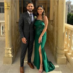 a man in a suit and woman in a green dress posing for a photo together