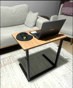 a laptop computer sitting on top of a wooden table in front of a couch with pillows