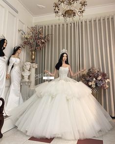 three women dressed in white gowns standing next to each other and one wearing a tiara