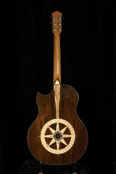 an acoustic guitar with a wheel on it's back and neck, sitting in front of a black background