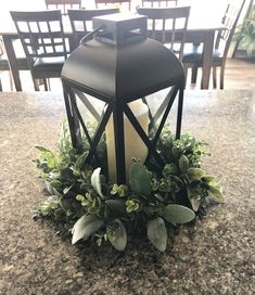 a candle is lit on top of a table surrounded by greenery and chairs in the background